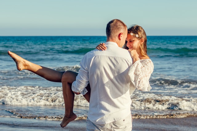 Groom picking up bride at the beach