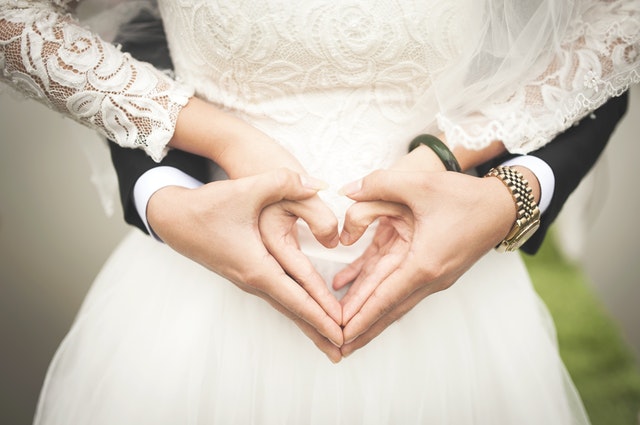 bride and groom making love signs with the hands