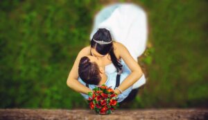 bride holding red bouquet while kissing groom